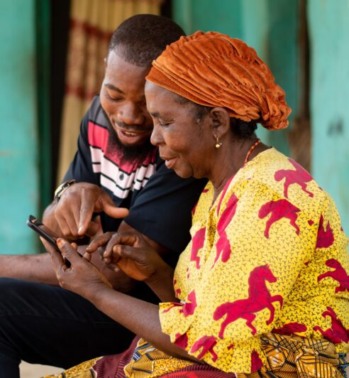 young african man assisting an elderly woman using her phone