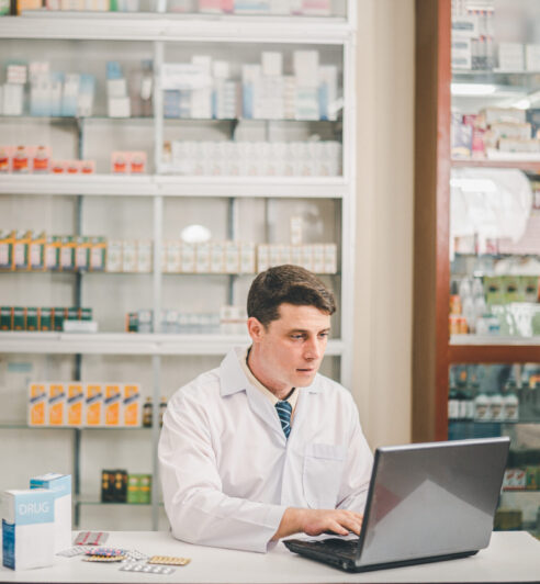 Male pharmacist checking, analyzing or Checks Inventory of Medicine, Drugs, Vitamins and checking prescription drugs for patients in modern pharmacy